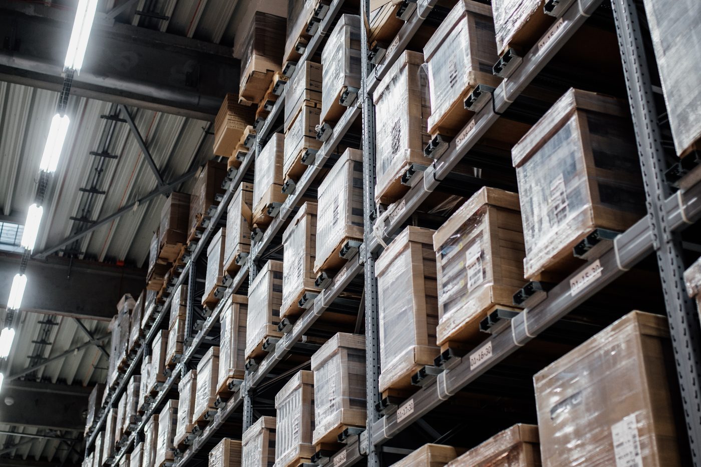 Warehouse racking holding wrapped, labelled stock marked with location codes.