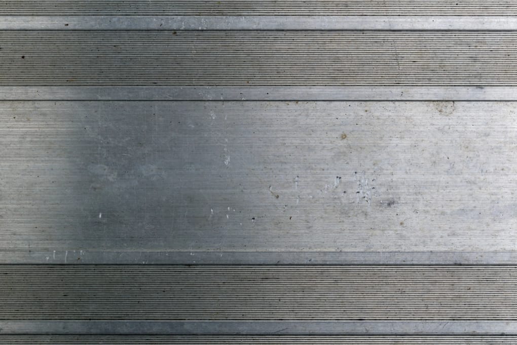 A machined aluminium plate with horizontal tool marks, scuffs and light staining from use.